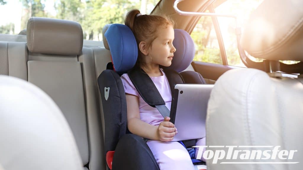 Small girl in child seat riding an airport taxi